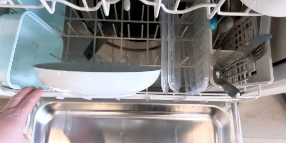 After a Dishwasher Leak Flooring Triage, Dry-Down, and Replacement Paths Open dishwasher with dishes and utensils inside, representing a kitchen after a dishwasher leak and the flooring triage process, including drying, damage assessment, and replacement options to restore the space safely and efficiently.