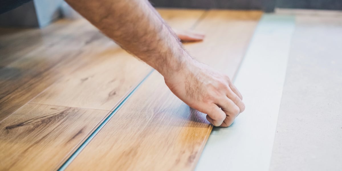 Commercial Office Acoustics Floor Strategy Hand installing laminate wood flooring planks