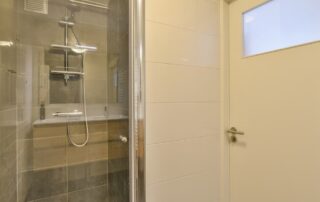 Modern glass-enclosed shower with tiled bathroom walls