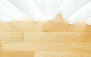 Sunlit wooden hardwood floor paired with sheer white curtains, addressing the question: Do You Need to Seal Hardwood for lasting beauty and protection?