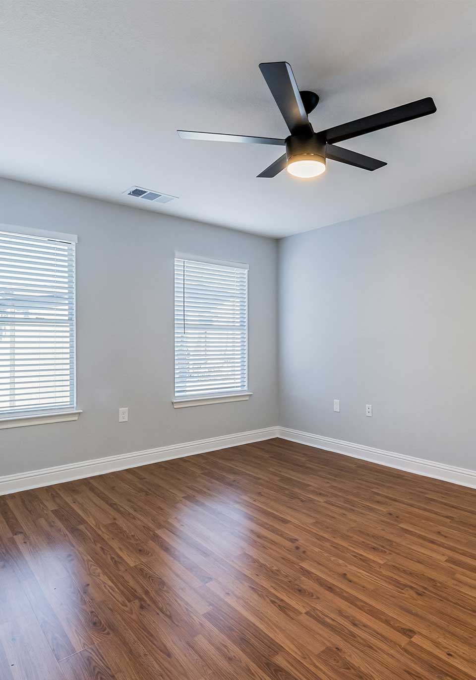Engineered Hardwood Flooring Denver Empty room featuring a newly installed engineered hardwood floor with rich wood grain and a smooth finish, complemented by neutral walls and a modern ceiling fan. Showcasing the beauty and craftsmanship of engineered hardwood flooring available in Denver homes.