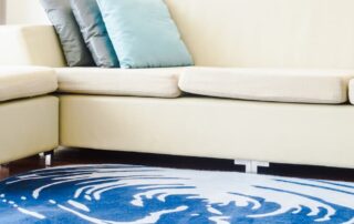 Modern beige sofa with blue pillows and a rug, offering tips on how to stop an area rug from bunching up on carpet for a smooth and tidy look.