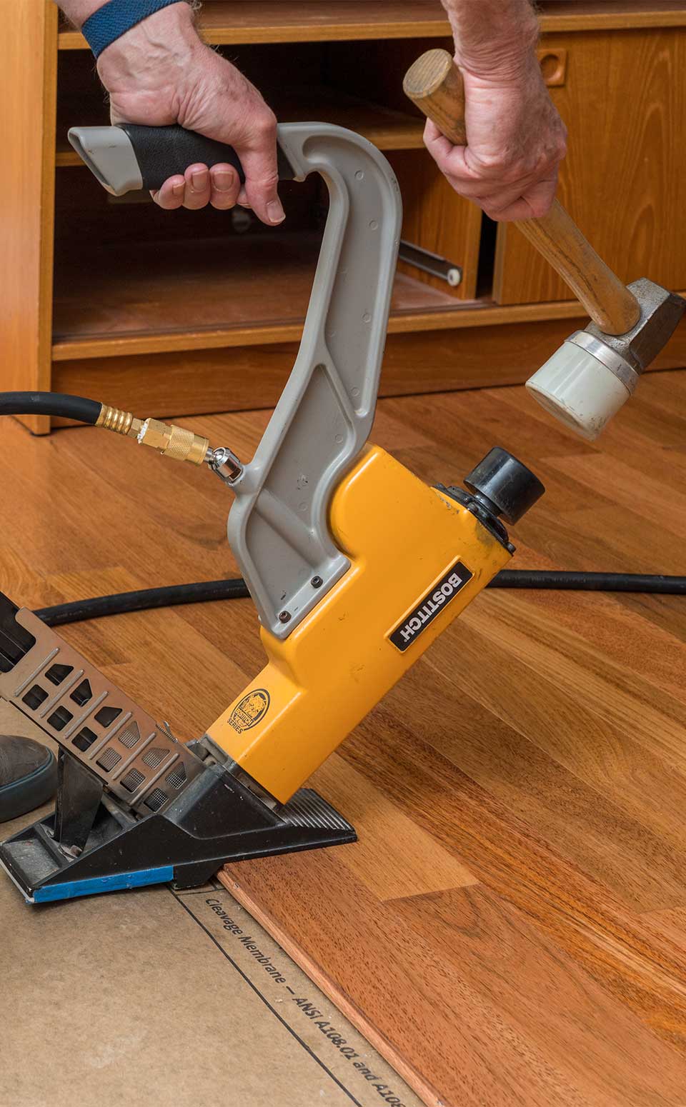 Solid Hardwood Flooring Denver Worker installing solid hardwood flooring with a flooring nailer in a Denver home. The image shows precise craftsmanship, smooth wood planks, and professional tools used for a durable, elegant finish — representing expert solid hardwood flooring installation services in Denver.