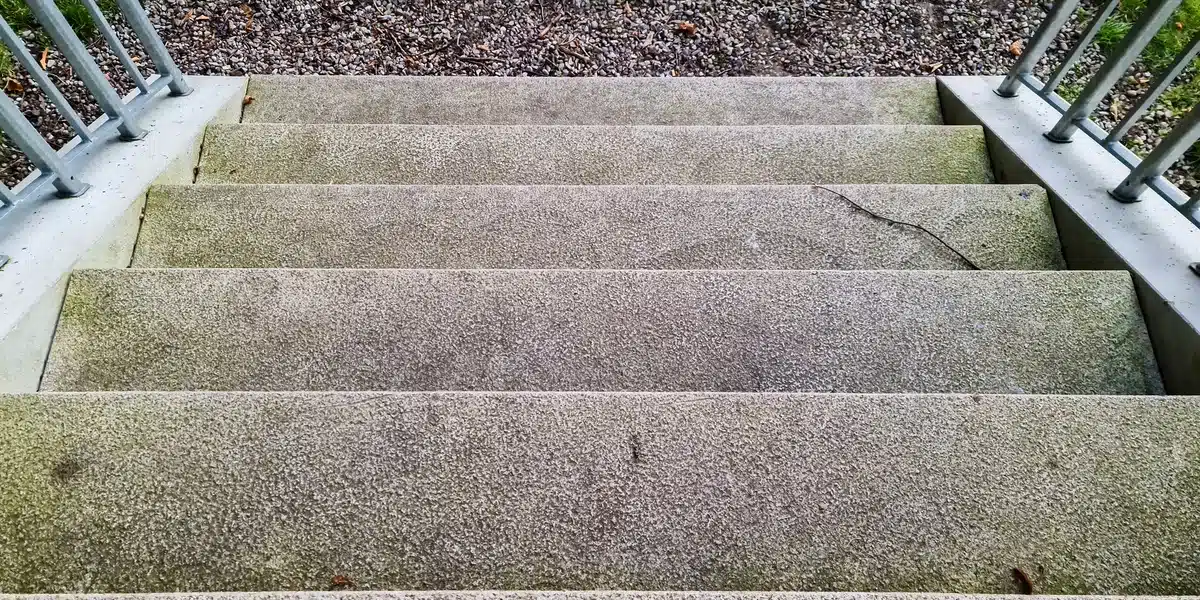 Stairs Too Slippery 7 Ways to Add Traction Without Killing the Look Concrete outdoor stairs with metal railings designed to improve safety and style, showing practical ways to add traction to slippery steps while maintaining a clean, modern appearance suitable for residential or commercial entrances.
