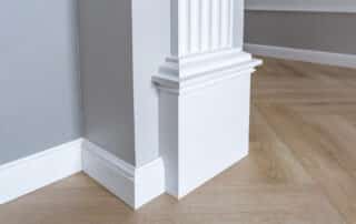 White baseboards and molding on wooden floor corners.