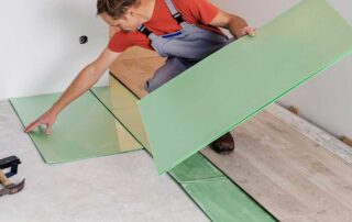 Man installing green underlayment for laminate flooring - Underlayments Demystified: Sound, Moisture, Thermal—Which to Use Where