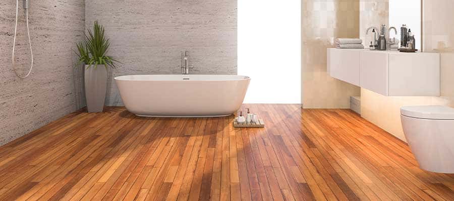 Modern bathroom with wooden flooring and a freestanding tub, exploring the best flooring option for bathrooms that combines style and water resistance.
